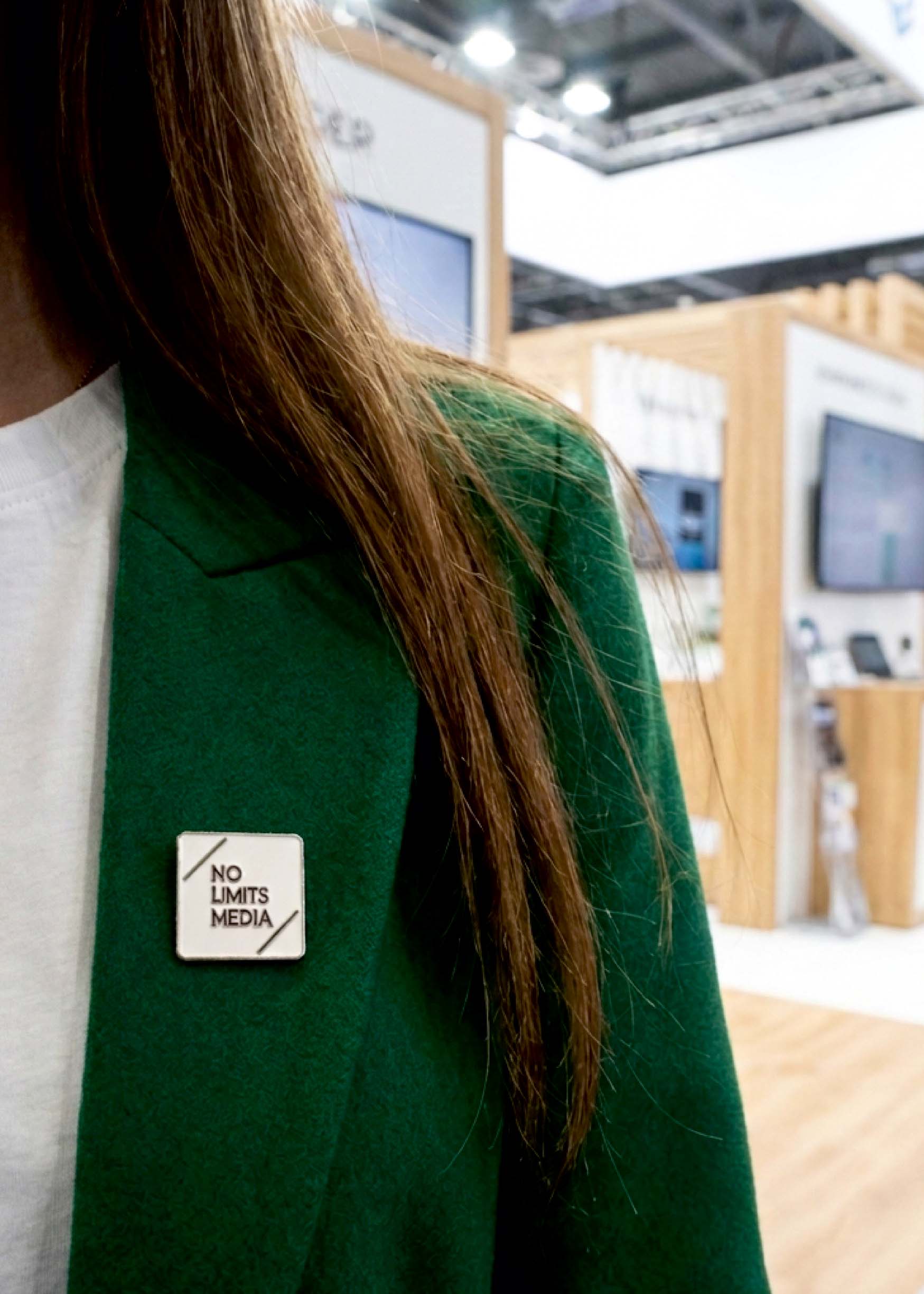 Individueller Firmenpin an einem grünen Blazer auf einer Messe