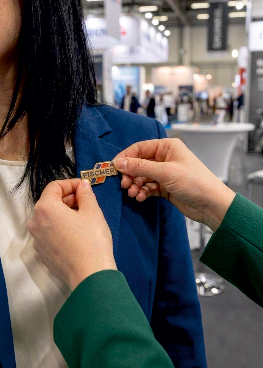 Ein individueller Pin wird auf einer Messe an einem Blazer befestigt